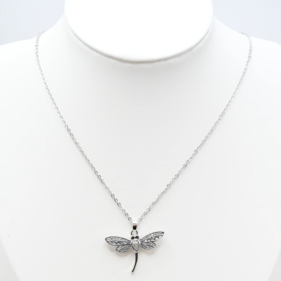 Collier argenté femme à pendentif libellule aux ailes ajourées serties de strass, sur buste blanc