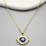 Gros plan du pendentif œil protecteur bleu nuit cerclé de pierres claires sur chaîne fine dorée