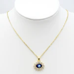 Collier doré femme à pendentif mauvais œil bleu entouré de strass, présenté sur un buste blanc