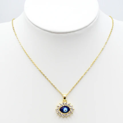 Collier doré femme à pendentif mauvais œil bleu entouré de strass, présenté sur un buste blanc