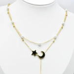 Collier double rang doré sur buste blanc, détail de l'étoile et du croissant de lune noirs