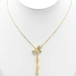 Collier doré femme à pendentif papillon pavé de strass et chute brillante, présenté sur un buste blanc