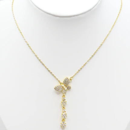 Collier doré femme à pendentif papillon pavé de strass et chute brillante, présenté sur un buste blanc