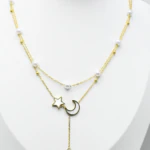 Collier doré femme double rang à perles blanches, étoile et lune nacrées et perle pendante, sur buste blanc