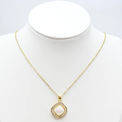 Collier doré femme à pendentif carré blanc nacré entouré de strass baguettes, présenté sur un buste