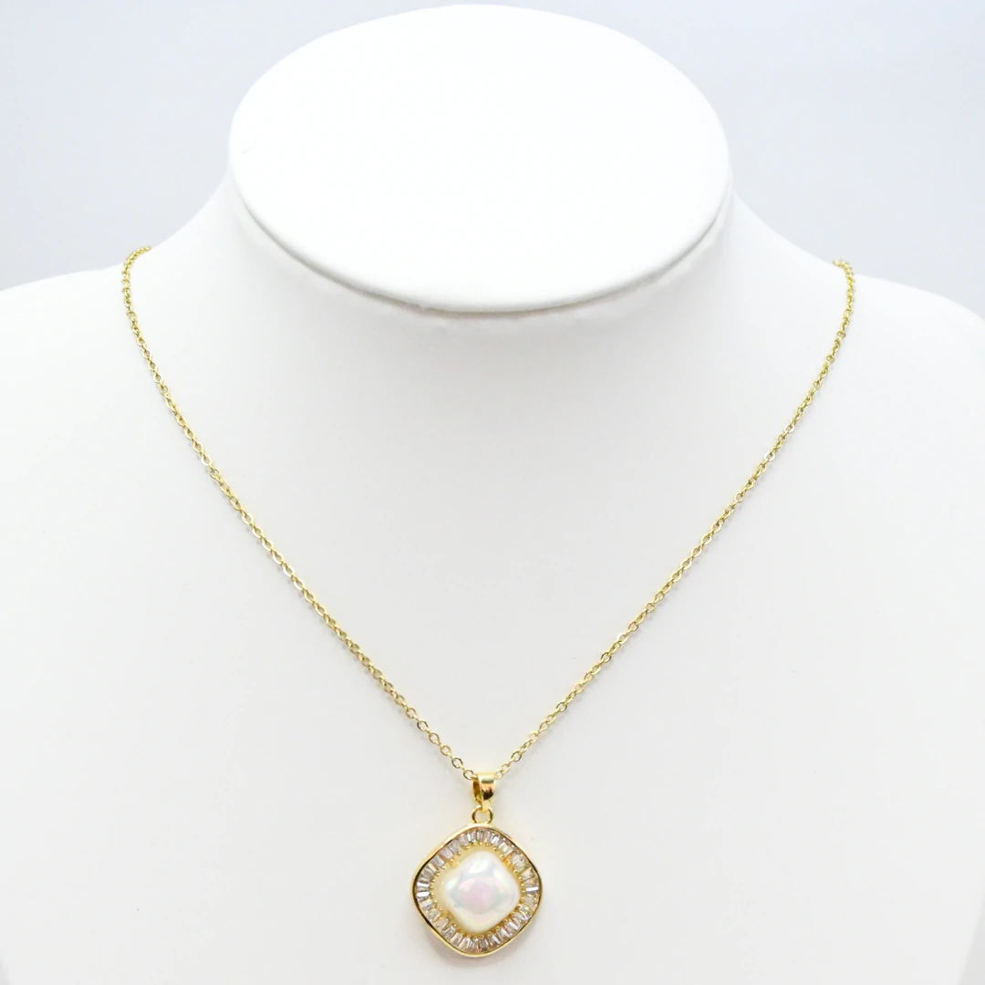 Collier doré femme à pendentif carré blanc nacré entouré de strass baguettes, présenté sur un buste