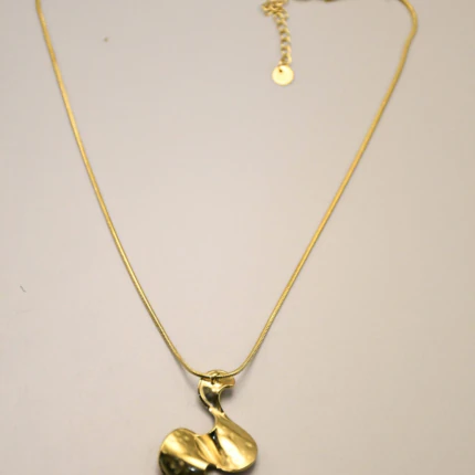 Collier chaîne serpent dorée à pendentif ondulé sculptural posé à plat sur fond beige