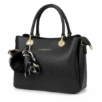 Sac à main noir grainé vu de trois quarts, pompon noir et foulard à motifs noués à l'anse
