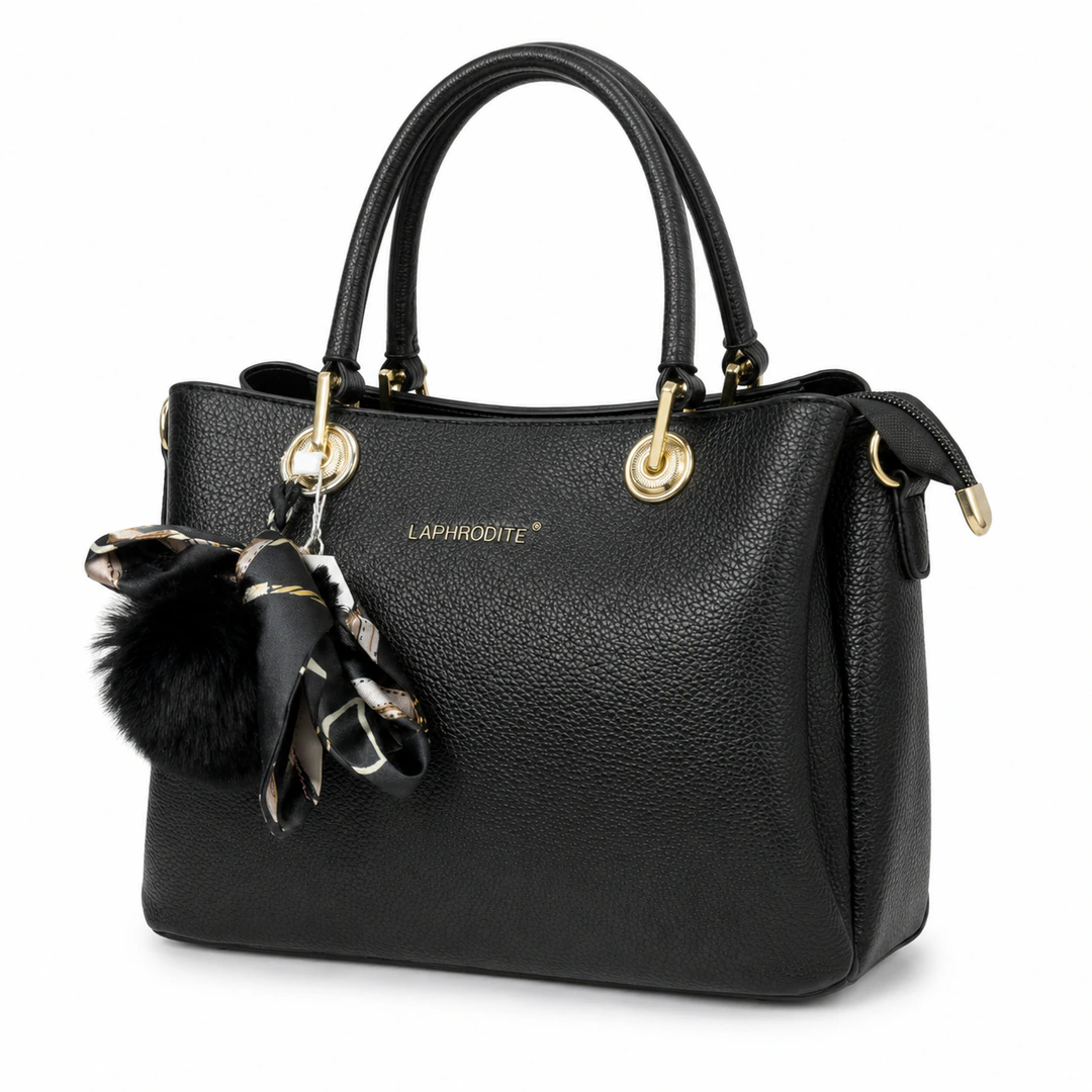 Sac à main noir grainé vu de trois quarts, pompon noir et foulard à motifs noués à l'anse
