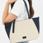 Femme portant à l'épaule le sac cabas bleu marine à panneau beige effet tressé