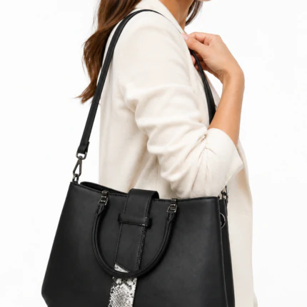 Femme portant à l'épaule le sac à main noir à détail effet serpent, avec une veste crème