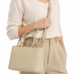 Femme portant le sac à main beige effet tressé en bandoulière avec un pull crème